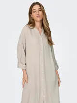Vestido camisero largo color beige, de lino, con cuello camisero, abotonado al frente y mangas largas con puños abotonados.