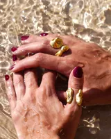 Anillo de diseño orgánico y macizo, realizado artesanalmente en bronce. Presenta una estructura abierta con dos piezas de forma irregular y textura rugosa.