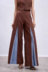 Pantalón ancho marrón con aberturas frontales que revelan un forro o panel interior de tela celeste. El pantalón se combina con un top a juego, creando un conjunto de dos piezas.
