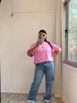 Remera rosa de corte cuadrado con logo bordado en rojo.