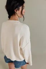 Cárdigan negro de silueta oversized, confeccionado en hilo de algodón suave con terminaciones acanaladas, escote en V, hombros caídos y mangas largas amplias.