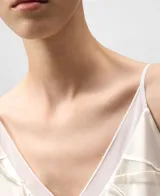 Top de mujer color crudo con escote pico y tirantes finos. Presenta una capa interior de tul y una capa exterior de tejido satinado con un efecto arrugado o drapeado texturizado.