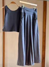 Conjunto de top musculosa corto y pantalón palazzo color gris oscuro, confeccionado en lycra de algodón. El pantalón es de corte evasé y tiene bolsillos laterales.