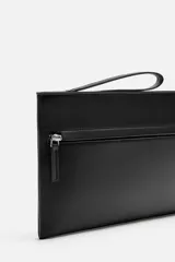 Bolso tipo sobre negro, con compartimento principal con cierre de cremallera, bolsillo interno con cremallera, bolsillo frontal con cremallera y asa de mano.