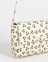 Bandolera color beige de cuerina con solapa, tag metálico y correa larga regulable.