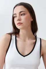 Musculosa de punto canalé color beige con cuello en V y ribete blanco en contraste.