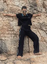 Pantalón negro de algodón, corte holgado y pierna ancha con pretina elástica. Presenta rayas blancas y celestes a los costados.