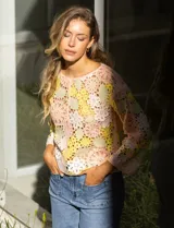 Buzo calado de tejido crochet con diseño floral en tonos pastel: rosa, amarillo y verde.