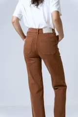 Pantalón jean color marrón, de tiro alto, corte recto y levemente acampanado. Presenta bolsillos delanteros y costuras visibles.