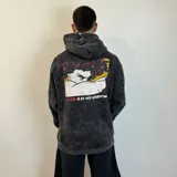 Canguro gris con efecto lavado, corte oversize, capucha con cordones y bolsillo tipo canguro. Estampado en el pecho con un diseño de un personaje de caricatura con la bandera de Argentina.