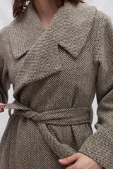 Tapado largo color beige con diseño de espiga, cuello solapa, cierre cruzado con cinturón y bolsillos laterales. Confeccionado en lana fina sin teñir.