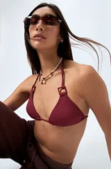 Top de bikini negro confeccionado en tejido con textura, de diseño triangular y detalle de aros cuadrados en los breteles. Se ajusta en cuello y espalda con lazos finos.