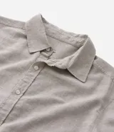 Camisa celeste de lino con cuello camisero, abotonadura frontal y mangas largas.