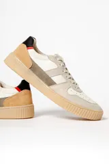 Zapatillas deportivas color beige con detalles en gris, blanco, negro y rojo.