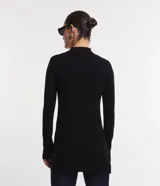 Suéter de punto color crema, con cuello alto, mangas largas con botones en los puños y bajo asimétrico.