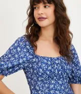 Vestido corto azul con estampado floral blanco, escote cuadrado, mangas cortas abullonadas y textura.