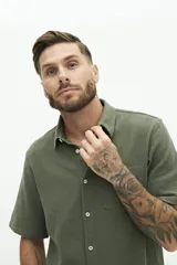 Camisa de manga corta color beige, con textura tipo crepé y cuello camisero.