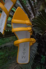 Sandalias de cuero color amarillo flúor con tres tiras finas con nudo y punta fina.