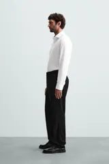 Camisa blanca de manga larga con cuello italiano abierto y puños abotonados. Presenta un corte slim fit y cierre frontal de botonadura.