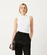 Musculosa blanca de punto con cuello alto y tirantes anchos.