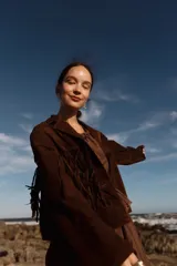 Chaqueta marrón de cuero gamuzado con flecos en la parte delantera y trasera.