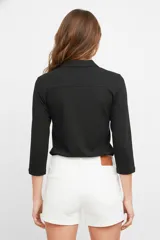 Remera azul marino de manga 3/4, con cuello camisero y cierre frontal parcial con botones. Diseño holgado con bolsillos frontales.