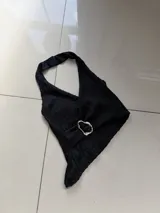 Top negro con cuello halter y detalle de aro metálico plateado en el frente.