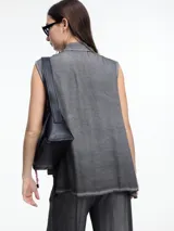 Camisa gris sin mangas confeccionada en viscosa teñida en frío, con efecto gastado. Tiene cuello clásico, cartera oculta y ruedo irregular más largo en los laterales.