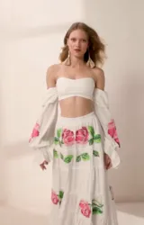 Falda larga de tiro alto color blanco con estampado de rosas rosadas y hojas verdes. Tiene volados en el ruedo y elástico en la cintura.