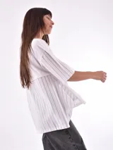 Remera blanca de corte holgado con mangas cortas y detalle de rayas verticales negras en mangas y laterales.