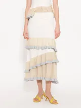 Falda midi de color blanco con paneles horizontales en beige y volados con borde plateado.