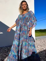 Vestido túnica largo de algodón con estampado de arabescos en tonos azules, rojos y verdes. Tiene escote en V con cordones y mangas acampanadas.