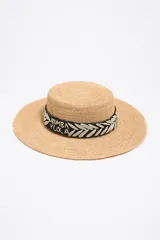 Sombrero de paja color beige con ala ancha y cinta decorativa negra y blanca con el logo de la marca.