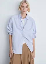 Camisa celeste y blanca a rayas verticales, de corte recto y mangas largas con puños abotonados.