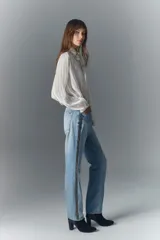 Jean de tiro alto de denim azul rígido con lavado claro localizado, bigotes y apliques laterales de strass.