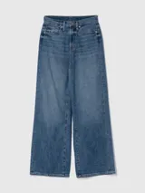 Pantalón de jean celeste de corte wide leg, con bolsillos delanteros y traseros, y tachas plateadas en los laterales.