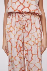 Pantalón de viscosa con un diseño estampado en tonos naranja y crudo, de corte ancho y elástico en la cintura.