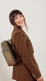 Mochila color marrón con doble asa de mano y correas traseras regulables. Presenta un bolsillo frontal con cierre y compartimento interno para iPad.