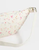 Riñonera color crema con estampado de flores pequeñas, correa ajustable con hebilla metálica, cierre superior y bolsillo frontal con cierre.