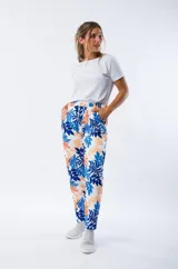 Pantalón babucha blanco con estampado de hojas en azul y naranja, con cintura elástica y cordón ajustable.