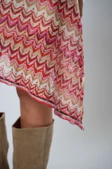 Minifalda roja con estampado de ondas en tonos rosados y beige, con corte irregular y cinturón marrón.