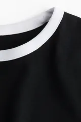 Remera negra entallada de punto suave con cuello y mangas con ribete blanco.