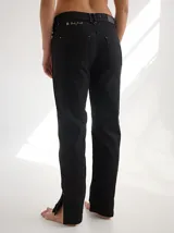 Pantalón negro de gabardina con alforzas verticales en los laterales y aberturas en el ruedo.