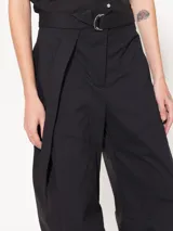 Pantalón negro de poplin 4way con lazo en la cintura, bolsillos ojales en delantero y espalda, pinza a la altura de la rodilla que le da una forma curvada, acceso mediante broche pantalonero, cierre y botón interno a tono de tela. Broches en el ruedo permiten ajustarlo.