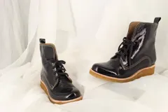 Botas tipo borcegos en charol corrugado, forradas en tela con detalles de cuero y cordones de algodón italiano.