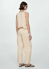 Pantalón color beige de corte recto y largo, con cintura elástica, bolsillos laterales y traseros, y bolsillos cargo en los laterales.