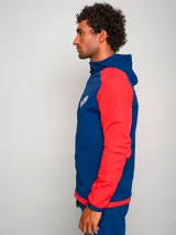 Campera deportiva con capucha, azul con mangas y hombros rojos, cierre frontal y escudo del Club Nacional de Football en el pecho.