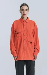 Camisa naranja de manga larga, estilo técnica con múltiples bolsillos delanteros y un bolsillo en la parte inferior de espalda, botones en cartera y mangas, calce oversize.