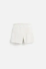 Bañador corto color blanco hueso de tejido técnico, con cintura elástica ajustable con cordón, bolsillos laterales y trasero.