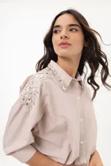 Camisa a rayas verticales color beige y blanco, con cuello clásico, manga larga abullonada y bordados de strass en hombros y cuello.